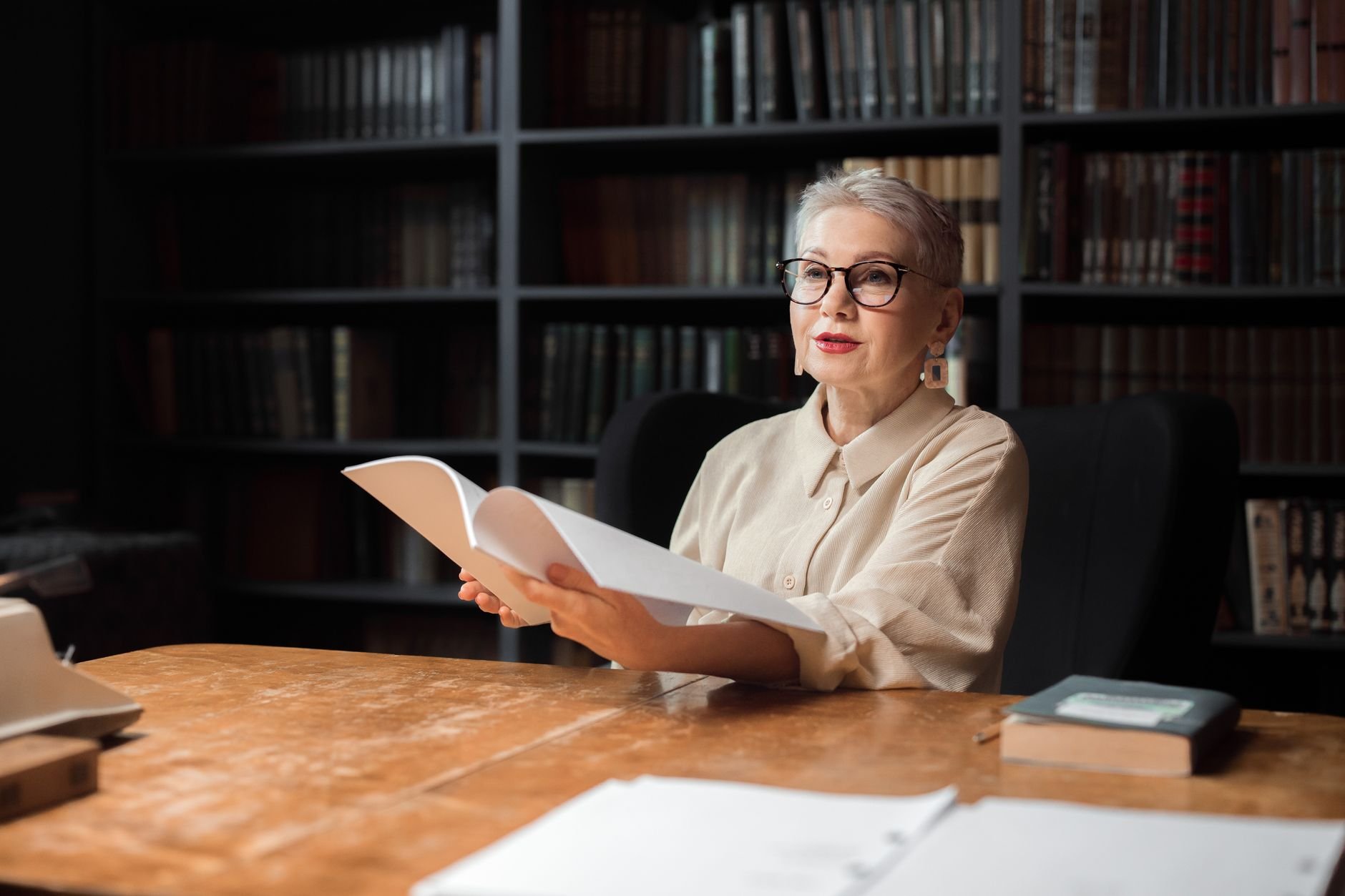Elderly woman engaging with a book in a cozy library environment.